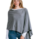 Woman wearing a Kerisma gray poncho over a white shirt and blue jeans on a light white background. Available at Be Charmed