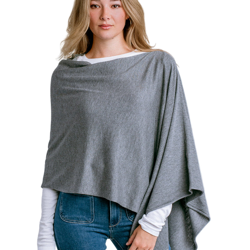 Woman wearing a Kerisma gray poncho over a white shirt and blue jeans on a light white background. Available at Be Charmed