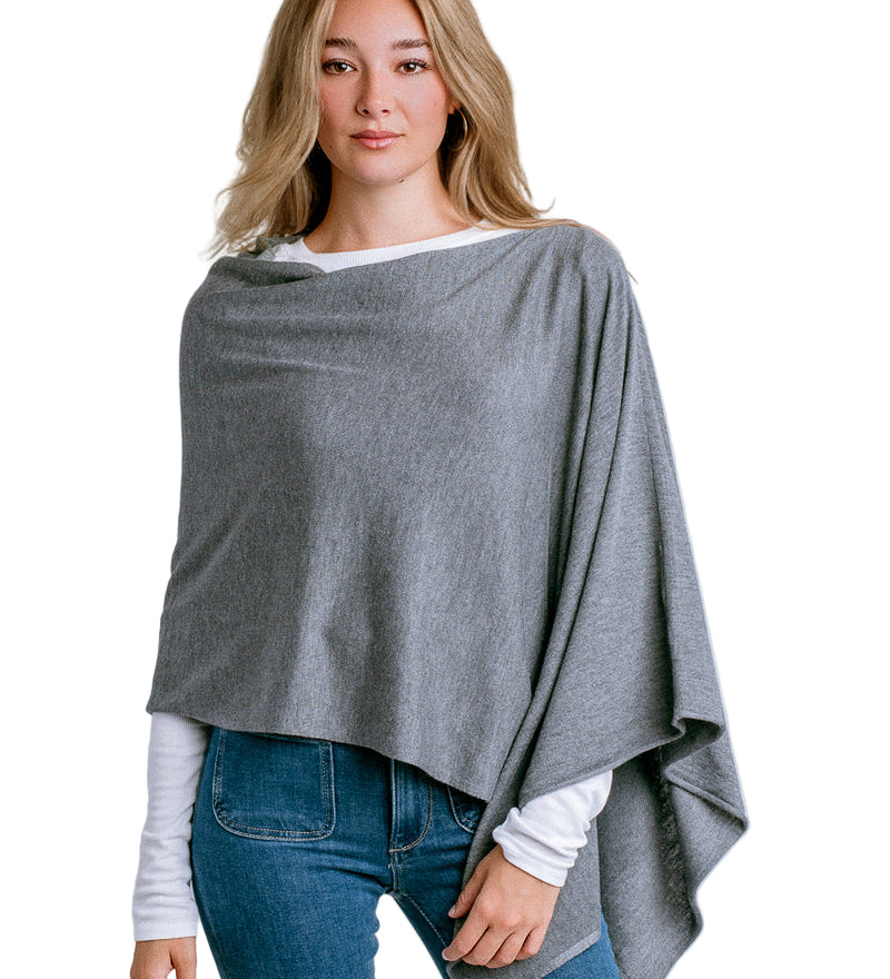 Woman wearing a Kerisma gray poncho over a white shirt and blue jeans on a light white background. Available at Be Charmed