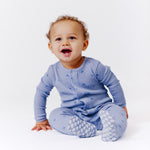 Child wearing a Magnetic Me waffle fabric footie in Soft Slate, available at Be Charmed.