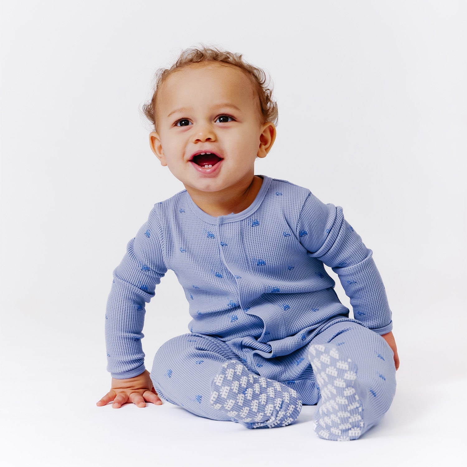 Child wearing a Magnetic Me waffle fabric footie in Soft Slate, available at Be Charmed.