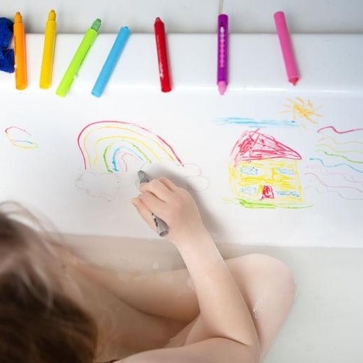 Kid using Tiger Tribe Bath Crayons set with colorful, washable crayons designed for drawing on tub walls during bath time. Safe and fun for kids. Available at Be Charmed.