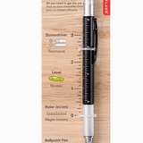 4-in-1 pen tool with ruler, screwdriver, level, and ballpoint pen on wooden packaging. Available at Be Charmed. 