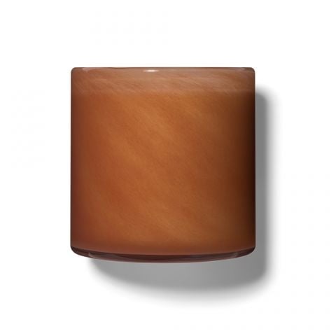 A square-shaped candle with a warm brown color and matte texture, set against a white background. Available at Be Charmed