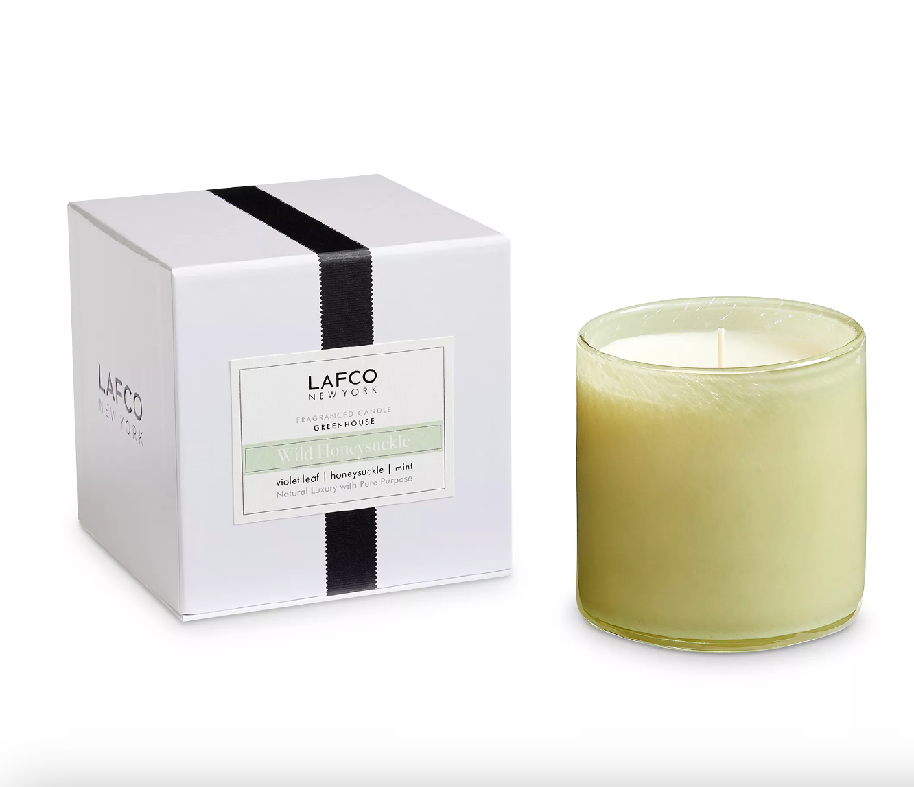 A LAFCO brand candle in a glass jar with a white label, alongside its white packaging box with black stripes. The candle is not visible in the packaging. Available at Be Charmed
