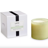 A LAFCO brand candle in a glass jar with a white label, alongside its white packaging box with black stripes. The candle is not visible in the packaging. Available at Be Charmed