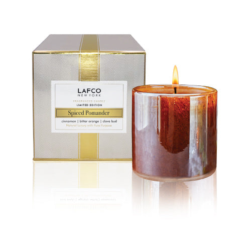 A LAFCO branded candle labeled 'Spiced Pomander' in a clear glass jar with a silver and gold label, next to its box packaging. Available at Be Charmed