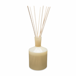 A beige 6 oz reed diffuser with visible reeds and a round base, set against a white background. Available at Be Charmed