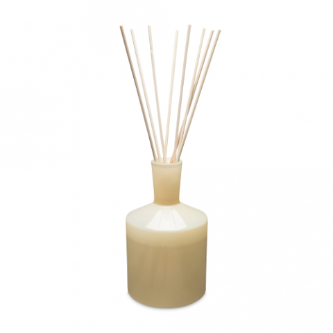 A beige 6 oz reed diffuser with visible reeds and a round base, set against a white background. Available at Be Charmed