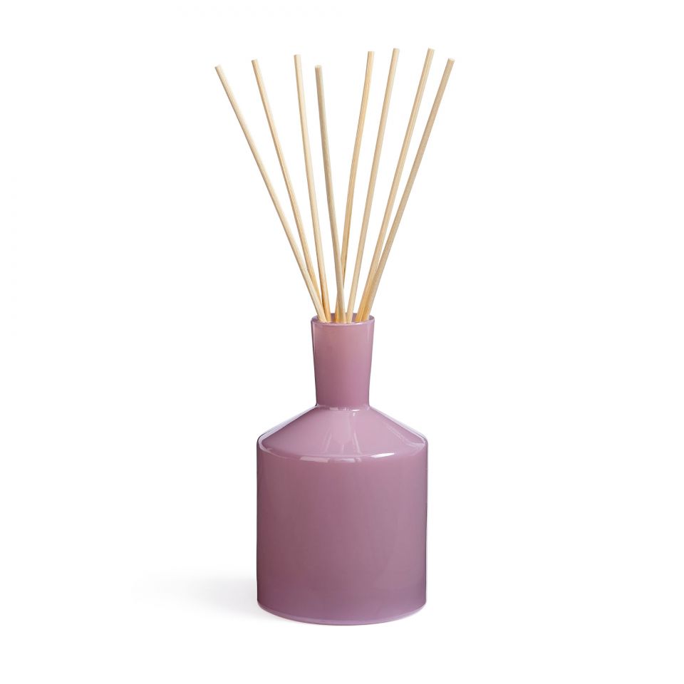 A purple LAFCO reed diffuser with several light brown reeds inserted into the top, sitting on a solid surface. Available at Be Charmed