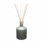 A LAFCO reed diffuser with a grey ceramic bottle and several light wooden reeds inserted, against a white background. Available at Be Charmed