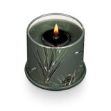 Candle in a green container with floral design on a white background. Available at Be Charmed