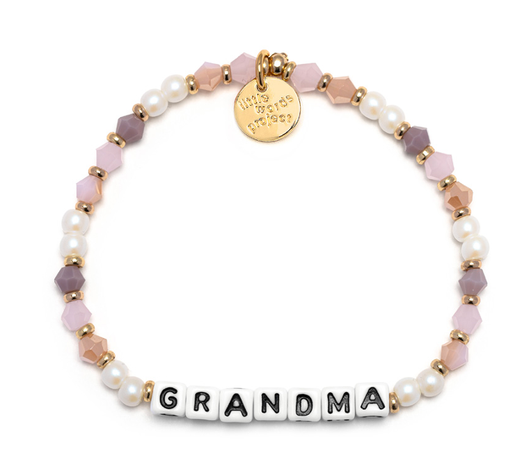 A beaded bracelet with the word 'GRANDMA' written in block letters, featuring peachy love colors and a gold charm. Available at Be Charmed