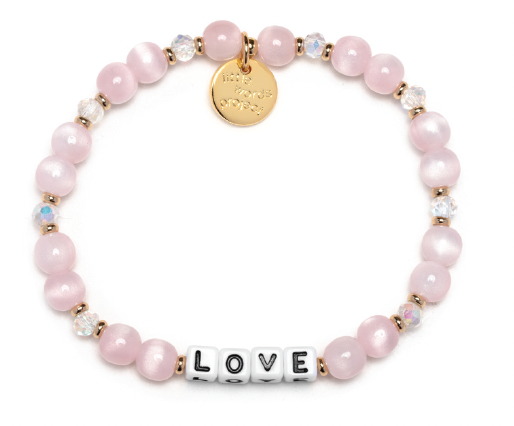 Pink beaded bracelet with a gold tag and 'LOVE' charm on a white background. Available at Be Charmed