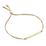 Lucky Feather Bestie Morse Code Bracelet featuring a gold-dipped bar engraved with 'Bestie' in Morse code, on an adjustable cord. Available at Be Charmed.