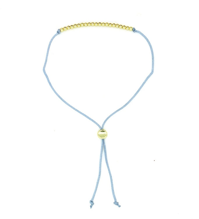 Lucky Feather Fun Twenty-One Milestone Birthday Bracelet featuring 21 gold-dipped beads on an adjustable cord, symbolizing each year. Available at Be Charmed.
