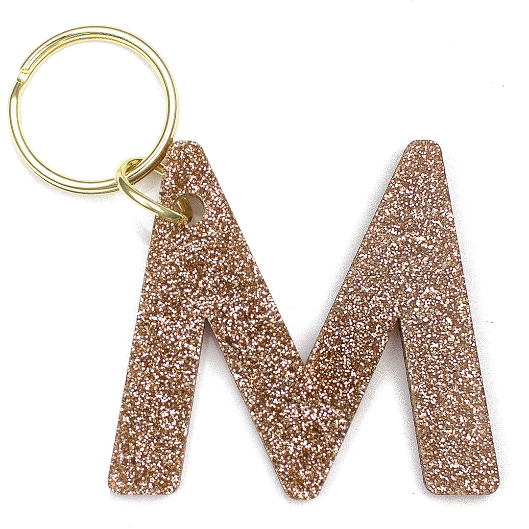 Lucky Feather Initial M Keychain featuring glittery acrylic letter charm with gold-tone hardware, personalized for each letter. Available at Be Charmed.