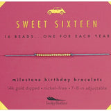 Lucky Feather Sweet Sixteen Milestone Birthday Bracelet on card featuring 16 gold-dipped beads on an adjustable cord, symbolizing each year. Available at Be Charmed.