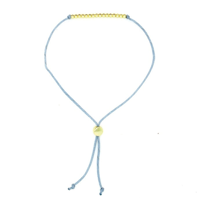 Lucky Feather Sweet Sixteen Milestone Birthday Bracelet featuring 16 gold-dipped beads on an adjustable cord, symbolizing each year. Available at Be Charmed.