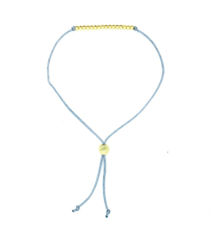Lucky Feather Sweet Sixteen Milestone Birthday Bracelet featuring 16 gold-dipped beads on an adjustable cord, symbolizing each year. Available at Be Charmed.
