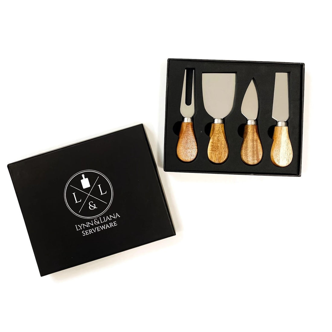 A set of four cheese knives with acacia wood handles, displayed in an open black gift box with the Lynn & Liana logo. Available at Be Charmed