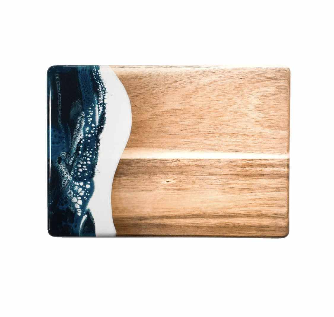 Wooden cutting board with a blue and white abstract design on a white background. Available at Be Charmed