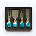 Set of four cheese knives with turquoise and wood handles in a black box on a white background. Available at Be Charmed