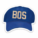 Blue cap with 'BOS' sticker against a white background. Available at Be Charmed