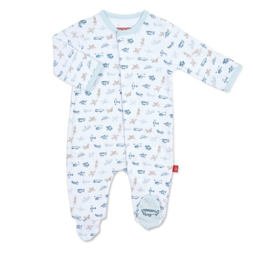 A white Magnetic Me baby footie with an airplane pattern and magnetic closures. Available at Be Charmed