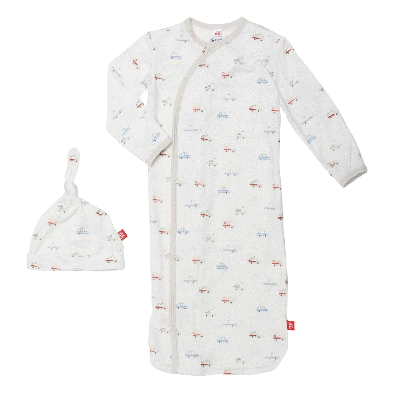 A white magnetic me baby gown with a pattern of cars and trucks, accompanied by a matching hat, both with magnets for easy dressing. Available at Be Charmed