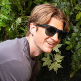 Man wearing Goodr Underwater Thunder Plunder Sunglasses featuring vibrant transparent teal frames and green polarized lenses, built for active comfort and bold beachside flair, available at Be Charmed