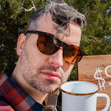 Man wearing Goodr Nine Dollar Pour Over Sunglasses with rich coffee-brown frames and polarized lenses, inspired by premium brews and built for performance, available at Be Charmed