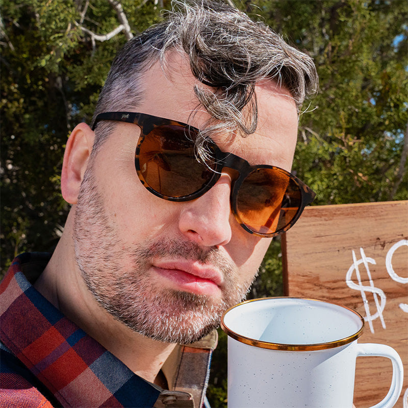 Man wearing Goodr Nine Dollar Pour Over Sunglasses with rich coffee-brown frames and polarized lenses, inspired by premium brews and built for performance, available at Be Charmed