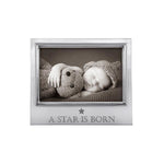 A silver-colored aluminum picture frame with a photo of a baby and a teddy bear, and the text 'A Star Is Born' on the bottom right. Available at Be Charmed