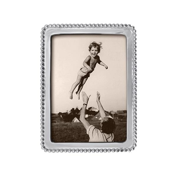 A silver-colored Mariposa beaded picture frame with a 5x7 aspect ratio, displaying a photograph of a child being lifted into the air by an adult. Available at Be Charmed