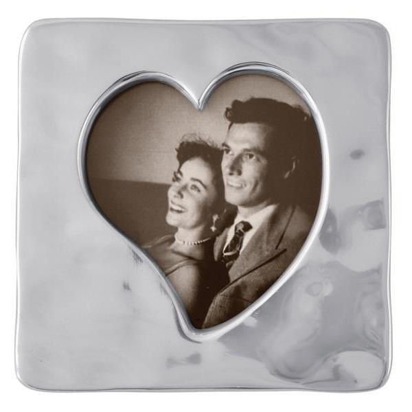A small square open heart-shaped picture frame with a photo of a couple peeking through the heart opening. Available at Be Charmed