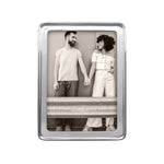 A recycled aluminum 5x7 Mariposa picture frame with a transparent front, displaying an image of two people standing close by a wall. Available at Be Charmed