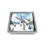 A silver-colored Mariposa napkin box with a ski design, featuring crossed skis and a snowy mountain backdrop. Available at Be Charmed