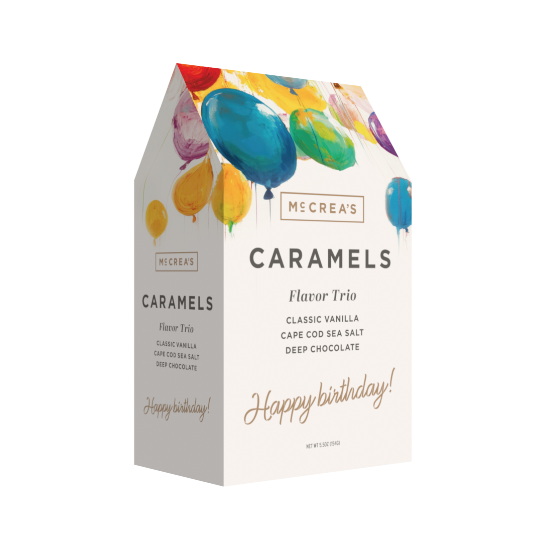 Box of McCrea's Caramels with colorful balloons on a white background. Available at Be Charmed