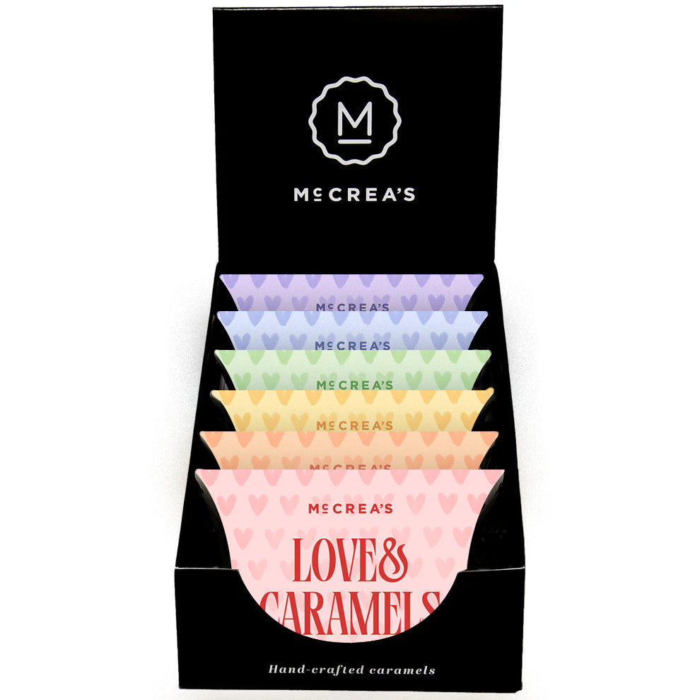 Display box of McCrea's Love & Caramels with colorful candy packages. Available at Be Charmed