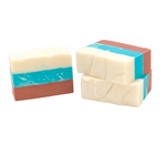 Two bars of handmade soap with a swirled pattern, predominantly white with blue and red streaks, stacked on top of each other. Available at Be Charmed