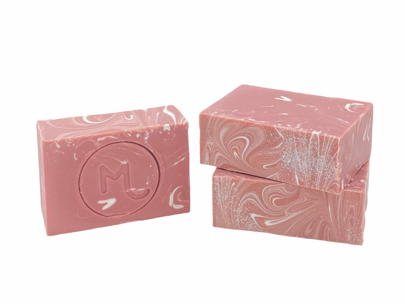 Two bars of Molly's Apothecary bar soap with a cranberry sparkle pattern, placed one in front of the other, with the brand's logo embossed on the top of each bar. Available at Be Charmed
