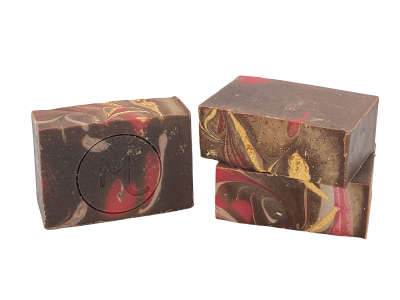 Two bars of Molly's Apothecary Bar Soap with a Frosted Winterberry pattern, featuring dark and light chocolate colors with red and gold accents. Available at Be Charmed