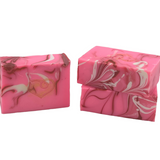 Two bars of Molly's Apothecary Lovespell bar soap, one stacked on top of the other. The top bar is pink with darker pink swirls, while the bottom one is white with darker white swirls. Available at Be Charmed