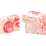 Two bars of handmade soap with a peppermint pattern in red and white colors. Available at Be Charmed