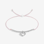 Pink bracelet with a silver heart charm on a white background. Available at Be Charmed
