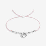 Pink bracelet with a silver heart charm on a white background. Available at Be Charmed
