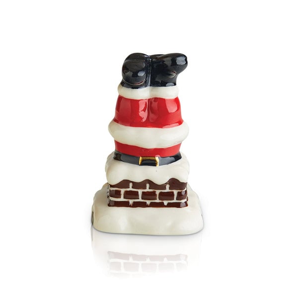 A miniature figurine of Santa Claus with a chimney-like base, primarily in red, white, and black colors. Available at Be Charmed