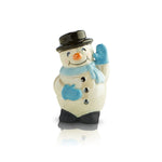 A ceramic snowman mini figurine with a smiling face, blue scarf, and black hat, standing on a beige base. Available at Be Charmed