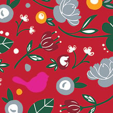 A patterned cocktail napkin featuring a red background with a variety of designs including flowers, leaves, a bird, and abstract shapes. Available at Be Charmed